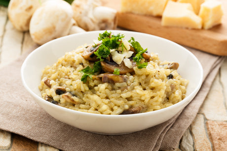 Un délicieux risotto crémeux aux champignons, servi dans une assiette blanche.